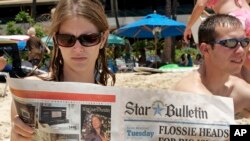 Turistas leen las últimas noticias sobre la llegada de la tormenta tropical Flossie a Hawai.