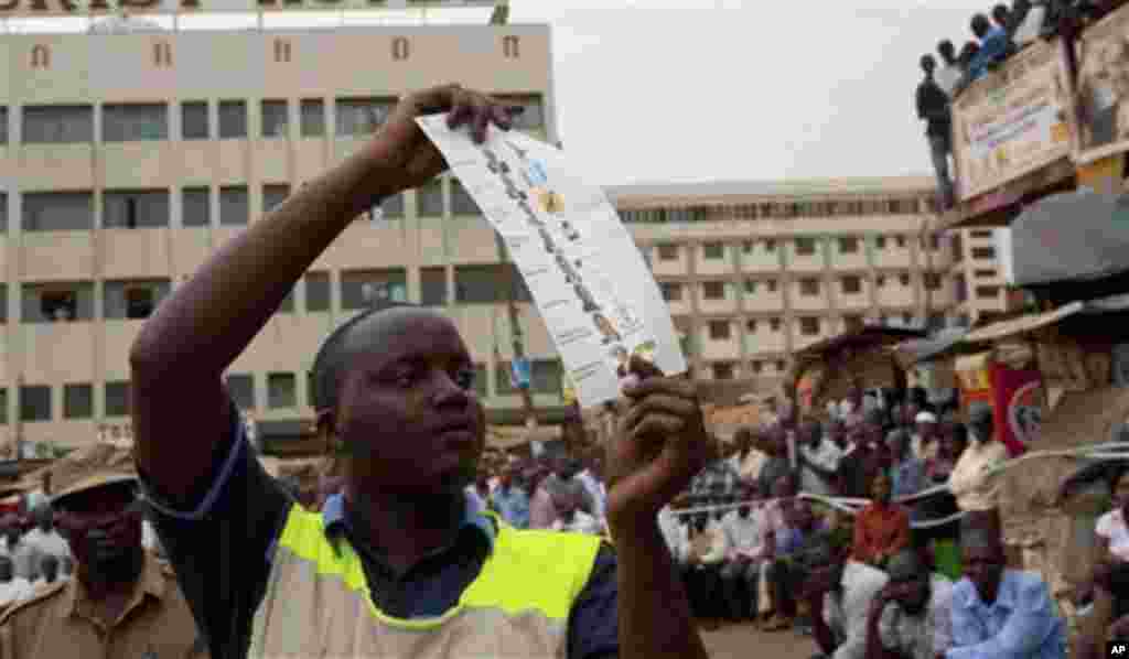 An electoral commission worker displays a ballot paper with a vote in favor of the opposition leader Dr Kizza Besigye, during the counting of votes observed by many onlookers at the Nakasero polling station in Kampala. Voters in Uganda faced the choice F