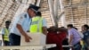 A police officer handles a ballot box as voters gather at a polling station during Kiribati's national elections in Tarawa on Aug. 14, 2024.