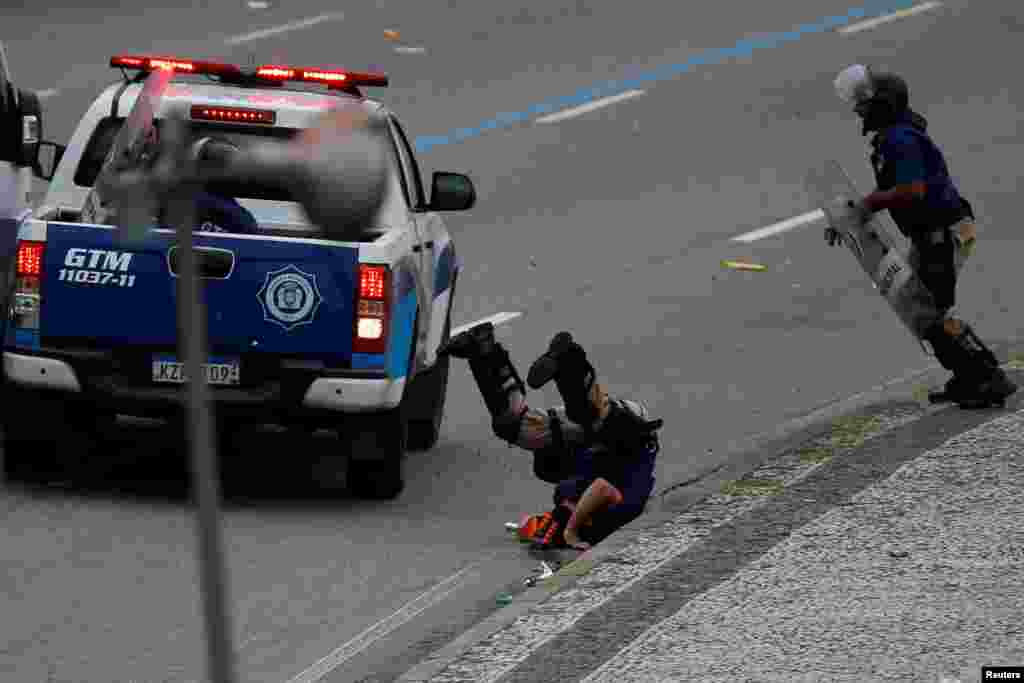 A riot police officer lands on the ground during clashes with fans at the Flamengo victory parade in Rio de Janeiro, Brazil, Nov. 24, 2019.