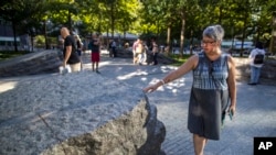 A visitor touches one of the granite slabs at the 9/11 Memorial Glade at the National September 11 Memorial & Museum in New York, Aug. 29, 2019. 