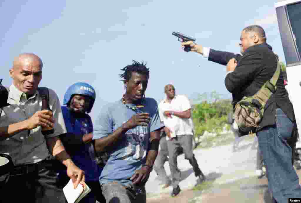 People run as Haiti&#39;s Senator Jean Marie Ralph Fethiere holds a gun in Port-au-Prince, Haiti, Sept. 23, 2019.