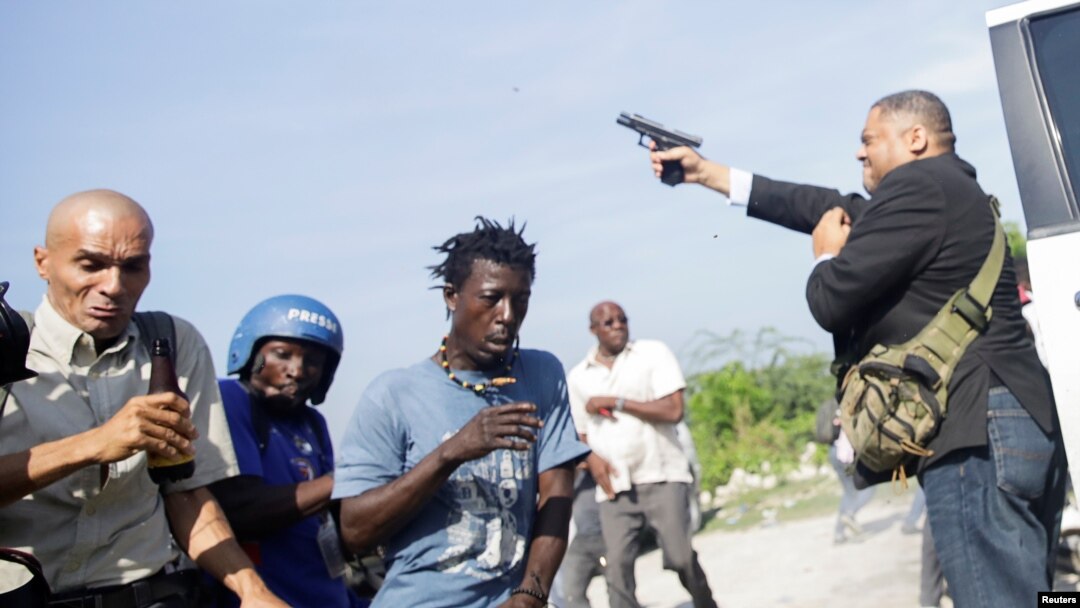People run as Haiti's Senator Jean Marie Ralph Fethiere holds a gun in Port-au-Prince, Haiti, Sept. 23, 2019.