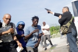 People run as Haiti's Senator Jean Marie Ralph Fethiere holds a gun in Port-au-Prince, Haiti, Sept. 23, 2019.