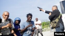 People run as Haiti's Senator Jean Marie Ralph Fethiere holds a gun in Port-au-Prince, Haiti, Sept. 23, 2019.