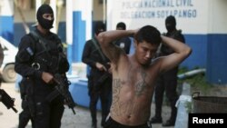 FILE - One of 13 suspected members of the 18th street gang is presented to the media after being arrested by the police under the charges of homicide and terrorism, in Soyapango, El Salvador.