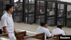 FILE - Islamist defendants stand behind bars in the case known as the "Kerdasa massacre'' in Cairo, Eygpt, June 23, 2014. 