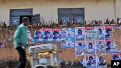 A Nigerian man hawks snacks along a street lined with destroyed posters advertising Presidential candidate Jonathan Goodluck at Jos, Apr 15 2011