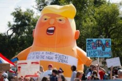 FILE - Demonstrators gather in front of an inflatable "Baby Trump" to protest the arrival of President Donald Trump outside Miami Valley Hospital after a mass shooting that occurred days earlier in the Oregon District, in Dayton, Ohio, Aug. 7, 2019.