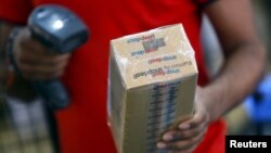 FILE - A worker of Indian e-commerce company Snapdeal.com scans barcode on a box after it was packed at the company's warehouse in New Delhi.