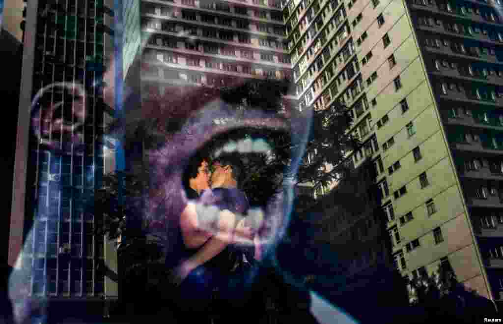 Kissing revelers are pictured reflected behind a showcase during the 19th Gay Pride parade along Paulista Avenue in Sao Paulo, Brazil, June 7, 2015.