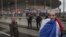A French supporter wrapped in his national flag passes by police officers guarding the Stade de France stadium prior to the international exhibition soccer match between France and Russia in Saint Denis, north of Paris, March 29, 2016.
