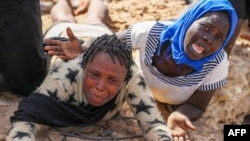 Para migran Afrika yang terlantar di pinggiran laut di perbatasan Libya-Tunisia di Ras Jedir menangis di hadapan para jurnalis, 26 Juli 2023. (Foto: Mahmud Turkia/ AFP)