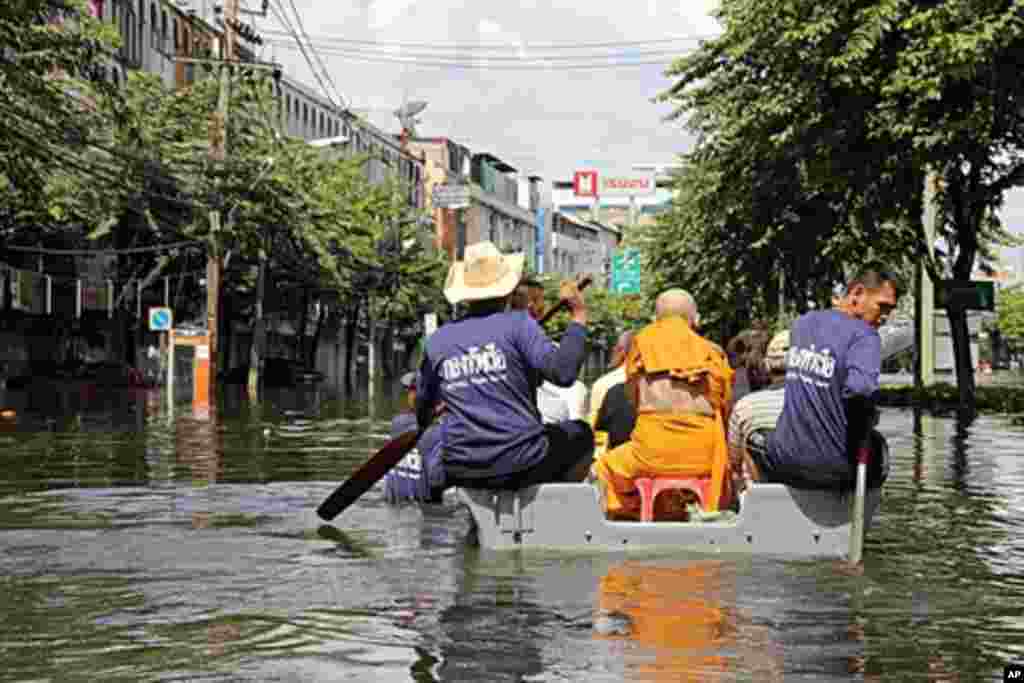 A navy boat carries a monk through a flooded neighborhood. The district of Bangkok borders Siriraj hospital, where the King of Thailand lives, and was flooded waist-deep, October 28, 2011. (VOA)