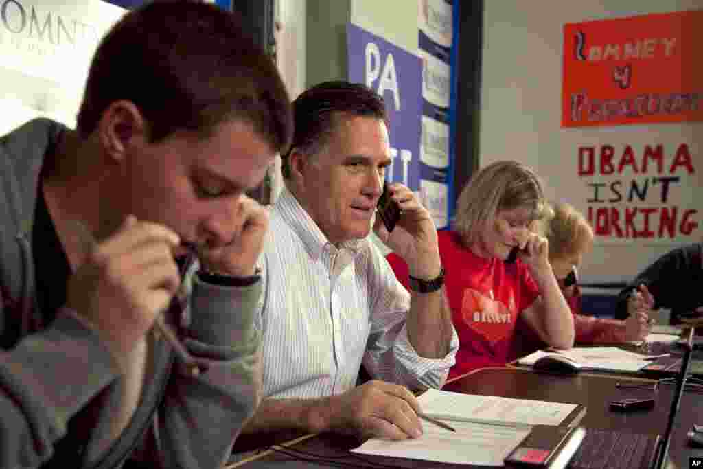 Republican presidential candidate, former Massachusetts Gov. Mitt Romney, center, flanked by campaign volunteers telephones a potential voter from a call center at his Pennsylvania campaign headquarters in Harrisburg, April 5, 2012. (AP)