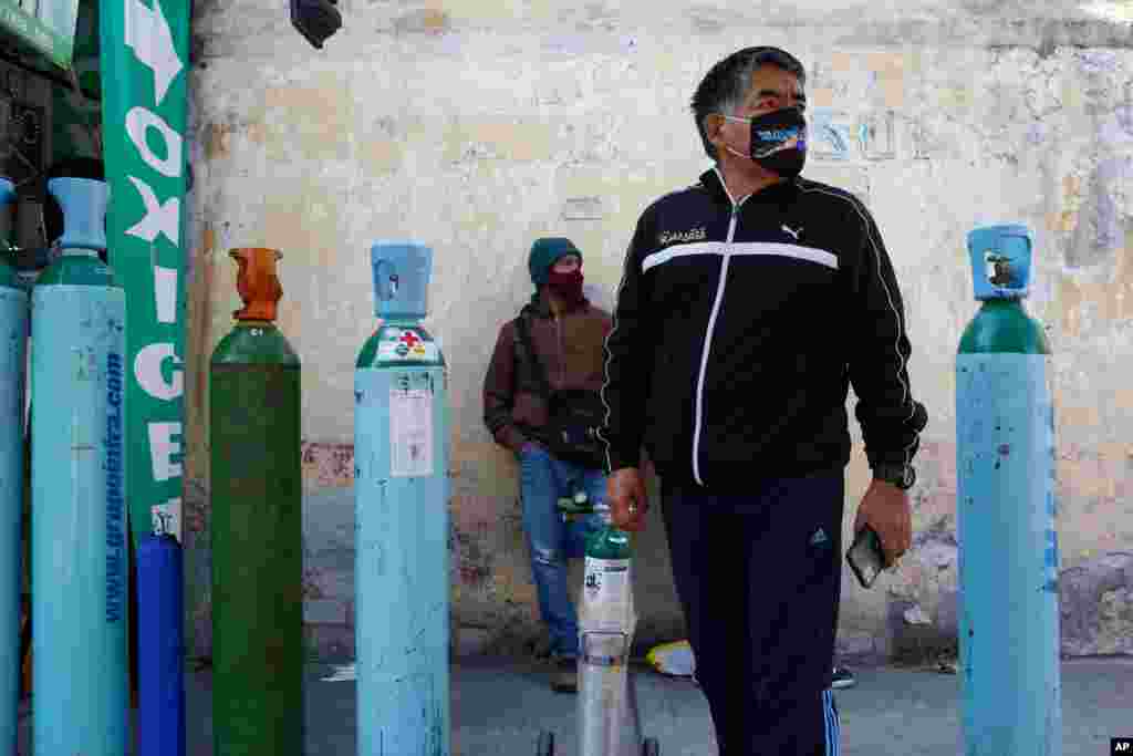 Jorge Perez lines up to refill an oxygen tank for a family member sick with COVID-19 in Mexico City, Dec. 27, 2020.