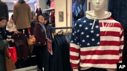 FILE - A woman tries out a sweater at U.S. retailer GAP's flagship store in Beijing, Jan. 10, 2019.