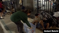 La voluntaria Olivia Muñoz de la organización "Hermanos de la Calle" reparte algunas mantas entre los desamparados del centro de la Ciudad de Miami, Florida. (Foto: Antoni Belchi / VOA)