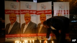 FILE - An man lights a candle during a candlelight vigil for Saudi journalist Jamal Khashoggi outside Saudi Arabia's consulate in Istanbul, Turkey, Oct. 25, 2018. 