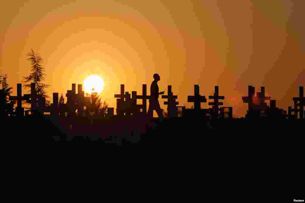 A man is silhouetted against sunset sky as he walks past the graves of soldiers killed in the 1974 Turkish invasion of Cyprus at the Tymvos Macedonitissas military cemetery in Nicosia, Cyprus, July 19, 2020.
