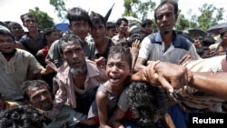 A boy is pulled to safety as Rohingya refugees scuffle while queueing for aid at Cox's Bazar, Bangladesh, Sept. 26, 2017. 