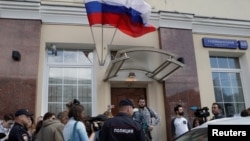 Police officers stand near a group of people gathered in front of a Moscow presidential campaign office for Russian opposition leader Alexei Navalny, where police are conducting an investigation, in Moscow, Russia, July 6, 2017.