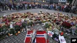 People mourn the victims of a shooting spree on an island in the countryside and a bomb attack around an improvised shrine in the capital Oslo July 23, 2011.