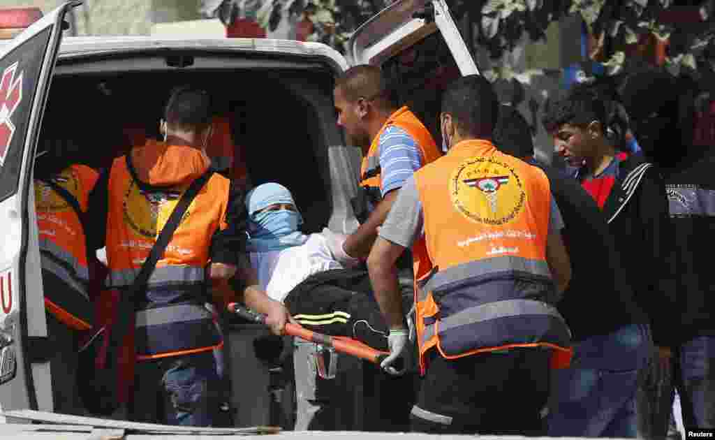 Palestinian medics carry a wounded man during clashes with Israeli troops at Qalandia checkpoint near the occupied West Bank city of Ramallah, Oct. 6, 2015.