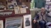 A tourist checks out the wares at a bouquiste stand. (Photo: L. Bryant / VOA) 