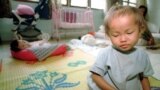 A young orphaned Cambodian infant girl infected with the HIV virus sits on a mat in the Phnom Penh Nutrition Center.