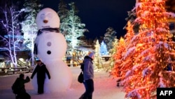 FILE - Tourists walk in the Santa Claus Village near Rovaniemi, Finnish Lapland, on Dec. 14, 2011. Research shows the Arctic is warming faster than other parts of the world due to climate change.