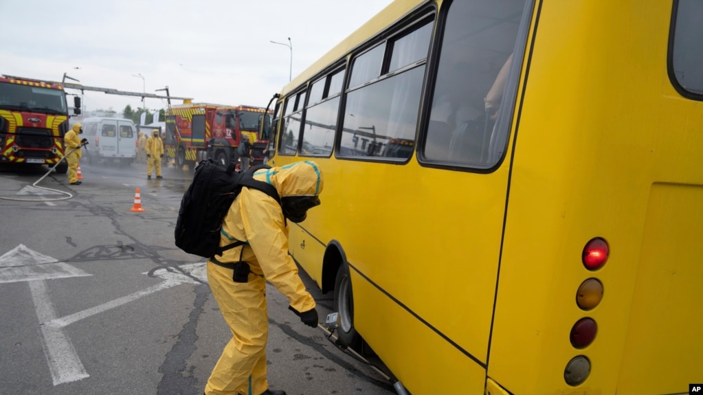 Український працівник у протирадіаційному костюмі перевіряє рівень радіації в автобусі під час тренувань у Запоріжжі, 29 червня 2023 р. AP Photo/Evgeniy Maloletka