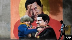 FILE - A man walks past a mural depicting Venezuelan late President Hugo Chavez, center, saluting and Venezuelan President Nicolas Maduro, right, holding a child in Caracas on Dec. 9, 2020.