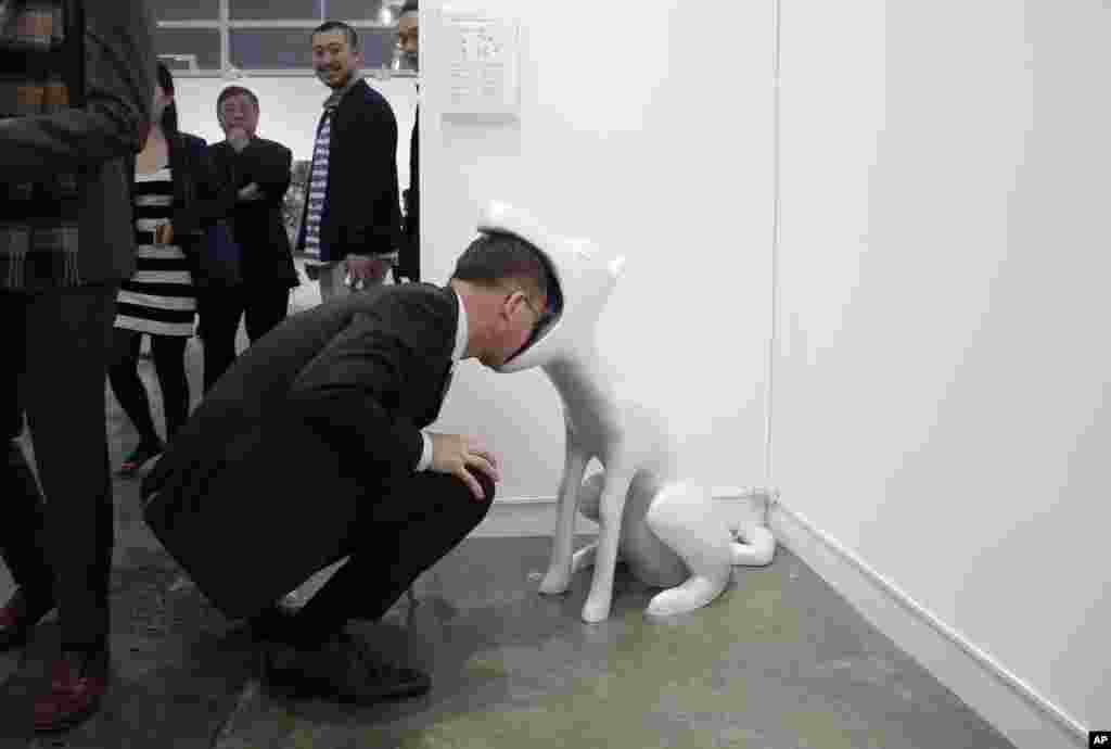 Seorang pria melihat instalasi seni &quot;Face to Face&quot; ciptaan seniman Taiwan Peng Hung-chih di Art Basel di Hong Kong (22/3). (AP/Kin Cheung)