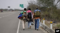 ARCHIVO - Tres migrantes venezolanos caminan en la autopista Panamericana hacia Lima desde Ecuador, el 26 de agosto de 2018.