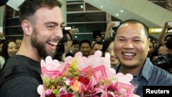 BuzzFeed writer Matt Stopera (L) of the U.S. is greeted by "Brother Orange" of China at an airport in Jieyang, Guangdong province March 17, 2015. 