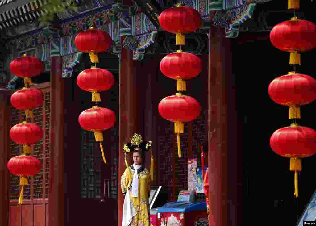 A restaurant promoter wearing a traditional Chinese costume waits for customers in Beijing.