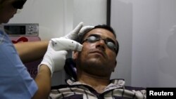 FILE - A man has acne removed from his face with a laser at a clinic in Baghdad, Iraq, June 2, 2015. Researchers have found that cream personalized with a person's own "good" bacteria may help ward off "bad" bacteria. 