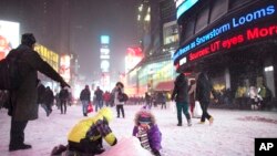 Children make a snow pile in Times Square, during a snowstorm, Thursday, Jan. 2, 2014, in New York. 