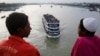 An overcrowded passenger boat navigates through Buriganga River as people watch from a bridge in Dhaka, Bangladesh, July 27, 2014.
