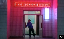 북한 평양 중구역 창전거리에 새로 문을 연 ‘황금벌상점' 종업원이 지난달 12일 가게 문을 열고 있다.