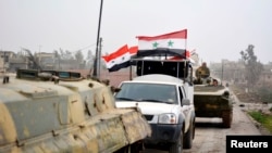 FILE - Fighters loyal to Syria's President Bashar Al-Assad ride on military vehicles and tanks after regaining control of Deir al-Adas, a town south of Damascus, Daraa countryside.