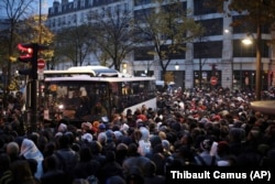 Migrants wait to board buses to temporary shelters, in Paris, Friday, Nov. 4, 2016.