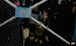 FILE - Children peer from the gate that closes off the section for foreign families who live in the Islamic State group's so-called caliphate, at al-Hol camp in Hassakeh province, Syria, March 31, 2019.