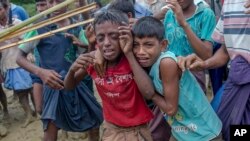 FILE - Rohingya Muslim boys, who crossed over from Myanmar into Bangladesh, cry as Bangladeshi men push them away during distribution of food aid near Balukhali refugee camp, Bangladesh, Sept 20, 2017.