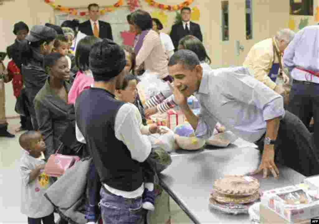 President Barack Obama, right, leans over to listens to hear an unidentified child speak as he helps pack food for Thanksgiving at Martha's Table, a local food pantry in Washington, Wednesday, Nov. 24, 2010. (AP Photo/Pablo Martinez Monsivais)