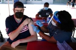 Chandler Millard, kiri, dari Alexandria, menerima vaksin Johnson & Johnson di klinik vaksinasi COVID-19 yang diselenggarakan oleh Washington Nationals sebelum pertandingan bisbol melawan Colorado Rockies, 9 September. 18, 2021. (Foto: AP)