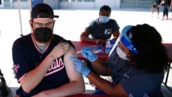 Chandler Millard, left, of Alexandria, Va., receives a Johnson & Johnson vaccine at a COVID-19 vaccination clinic hosted by the Washington Nationals outside of Nationals Park before a baseball game against the Colorado Rockies, Sept. 18, 2021.
