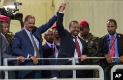 FILE - Eritrean President Isaias Afwerki, second left, and Ethiopia's Prime Minister Abiy Ahmed, center, hold hands as they wave at the crowds in Addis Ababa, Ethiopia, July 15, 2018.