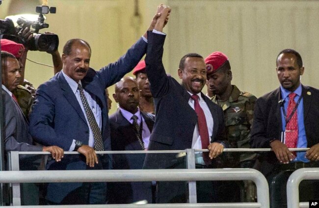 FILE - Eritrean President Isaias Afwerki, second left, and Ethiopia's Prime Minister Abiy Ahmed, center, hold hands as they wave at the crowds in Addis Ababa, Ethiopia, July 15, 2018.
